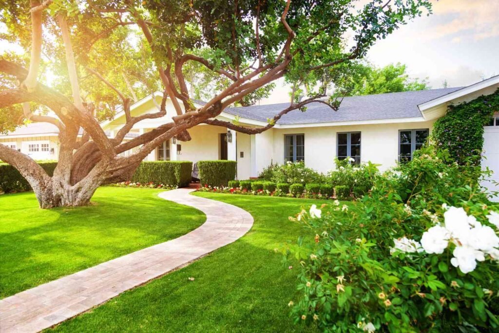 residential home with lush green grass, large trees, and nicely trimmed bushes