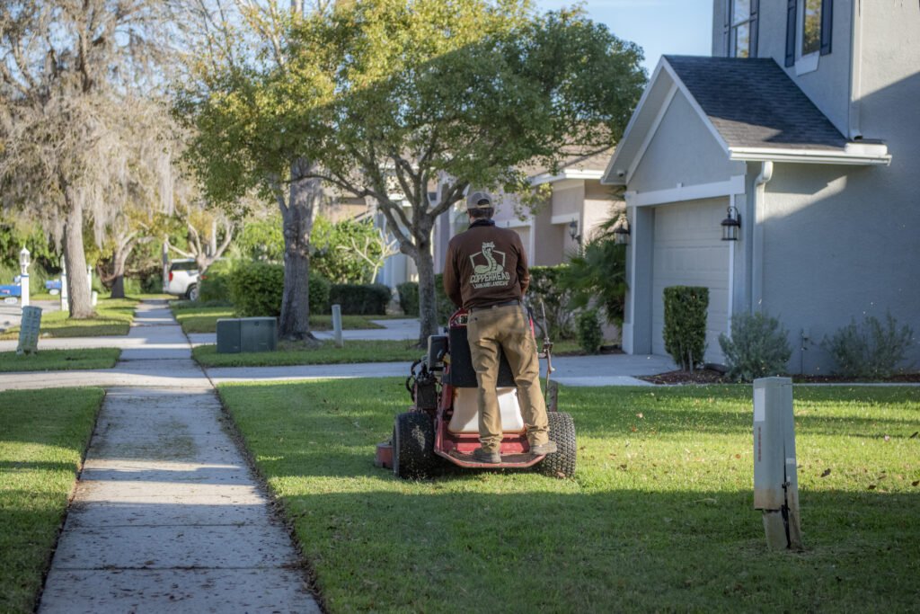Copperhead Property Maintenance Employee Mowing Lush Green Grass of a Residential Lawn in Connerton, FL