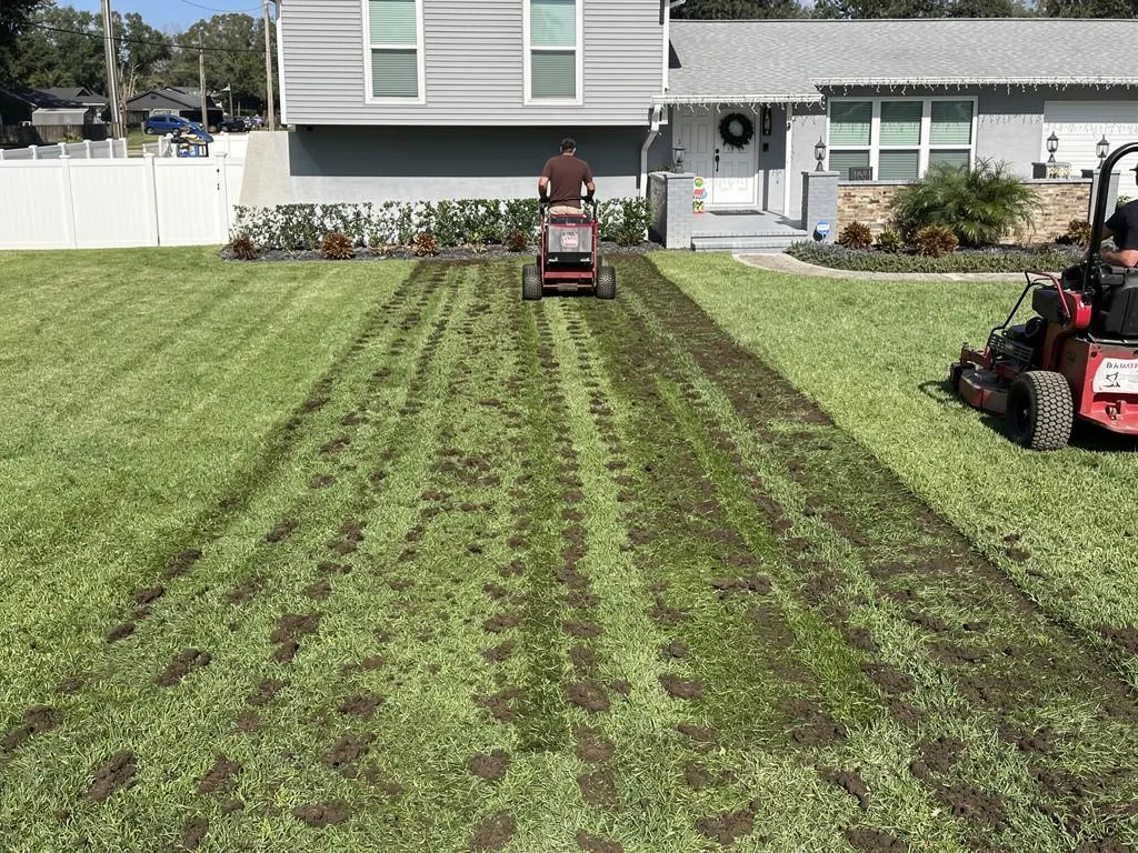 Aeration equipment pulling soil cores across a residential lawn